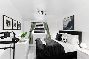 Een moderne slaapkamer met een bed, een bureau en een raam met gordijnen.