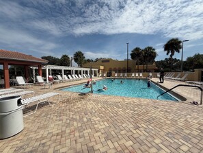 A swimming pool with lounge chairs and a covered area, surrounded by palm trees and a clear sky. - 2 mile Lake Sumter/1 mile Spanish  Springs/New to rental Aug '26. /3 mins pool (the villages)