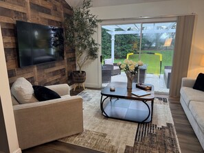 A living room with a flat-screen TV, a potted plant, a coffee table, and a sofa. - 2 mile Lake Sumter/1 mile Spanish  Springs/New to rental Aug '26. /3 mins pool (the villages)