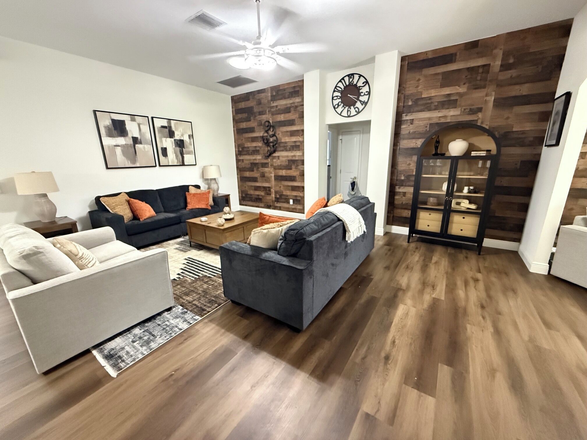 A living room with a sofa, armchair, coffee table, and a decorative clock.