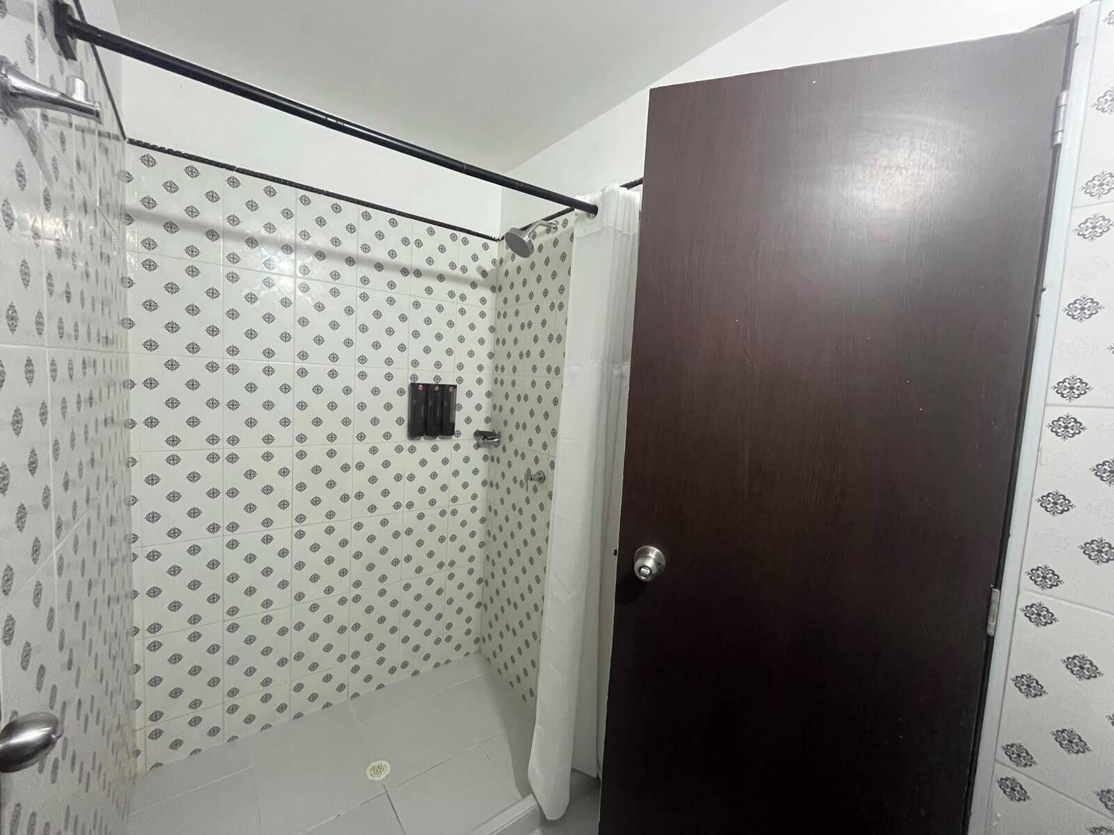 A bathroom with patterned tiles, a shower curtain, a door, and a towel rack.
