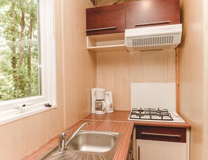 A compact kitchen with a sink, a coffee maker, and a stove. - Spacious Lakeside Chalet for 8 (Moncontour)