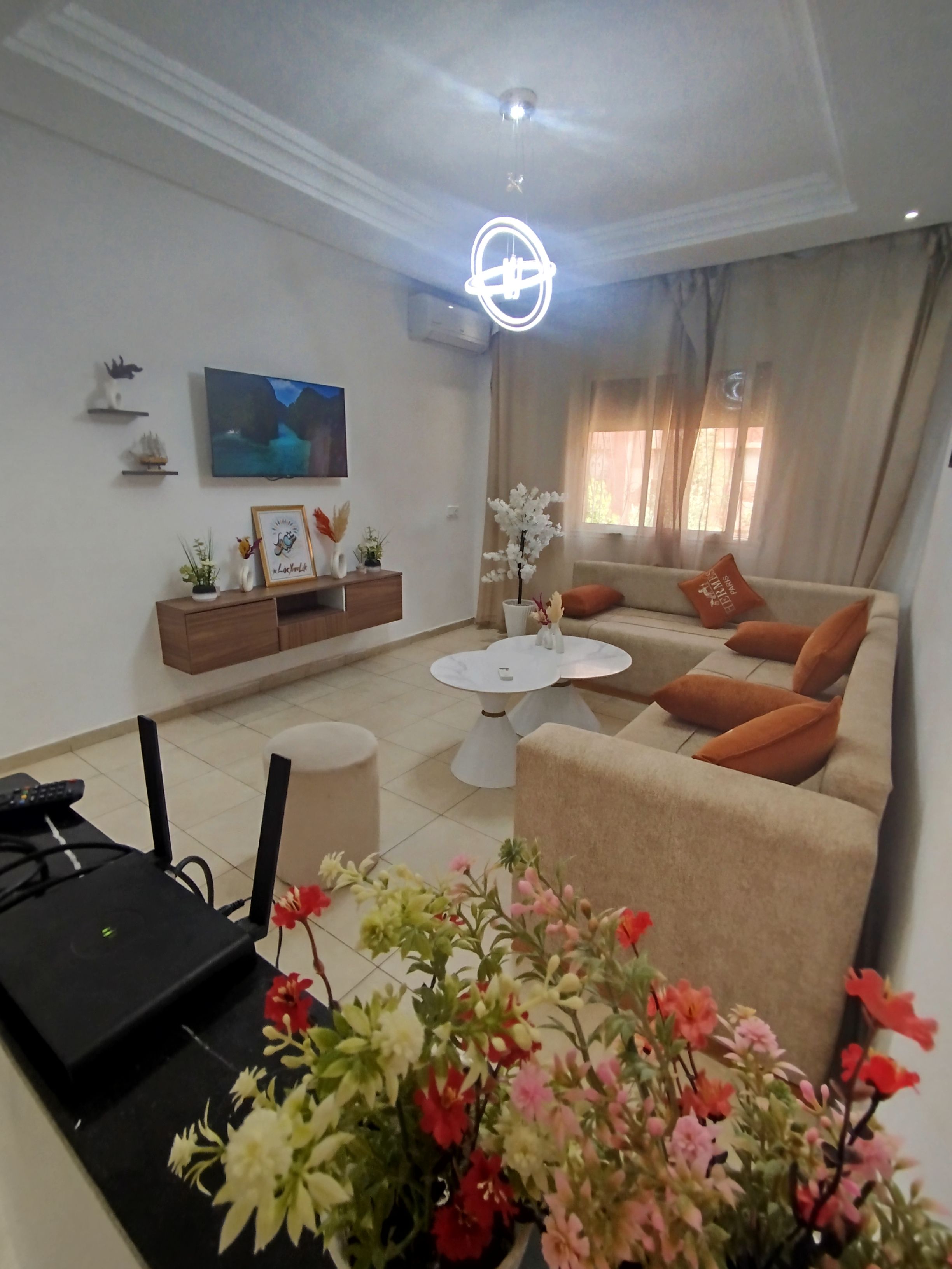 A living room with a sofa, coffee table, and a TV on the wall.