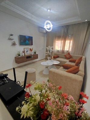 A living room with a sofa, coffee table, and a TV on the wall. - Large 3-Bedroom Apartment • Near Guéliz & the Airport • Fiber & Parking (Marrakech)