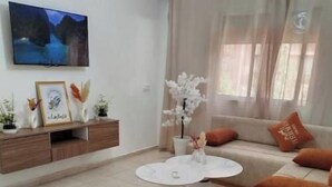 Un soggiorno con divano, tavolino, televisore montato a parete e mobile contenitore con oggetti decorativi.