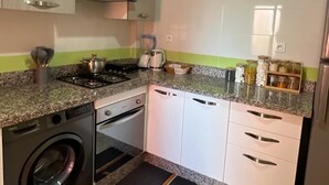 Een keuken met een wasmachine, fornuis en een koelkast.