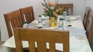 Een eethoek met een tafel voor vier personen, omringd door houten stoelen. Daarboven hangt een lijst met een schilderij aan de muur.