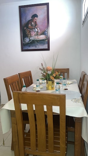 A dining area with a table set for four, surrounded by wooden chairs. A framed painting hangs on the wall above the table. - Large 3-Bedroom Apartment • Near Guéliz & the Airport • Fiber & Parking (Marrakech)