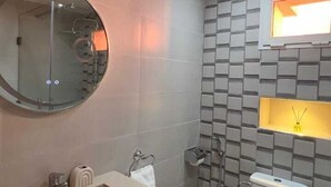 Un bagno moderno con uno specchio rotondo, un water e un lavandino.
