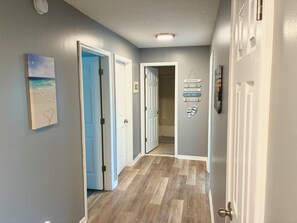 A hallway with wooden flooring, white doors, and a wall-mounted sign with flip-flops. - 3-bedroom townhome in charming St. Augustine Beach walking distance to the beach (St. Augustine Beach)