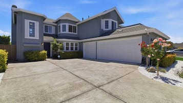A two-story house with a garage, a driveway, and a small garden with flowers.