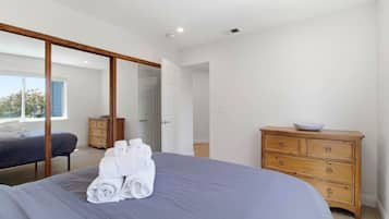 A bedroom with a bed, a wooden dresser, and a sliding door leading to another room.