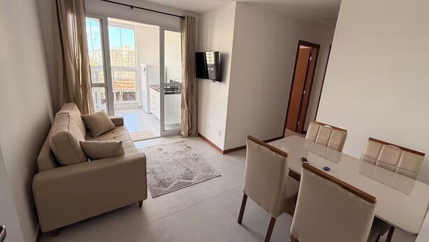 Un saló modern amb un sofà, taula de dinar, cadires i una televisió.