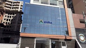Edifici de diversos pisos amb façana de vidre i un rètol que diu 'aloha' a la planta baixa.