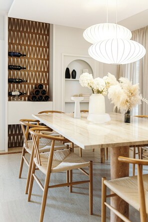 A dining area with a marble table, wooden chairs, a white vase with flowers, and a wine rack with bottles. - Luxurious Villa Ksenia with Pool Murter (Murter)