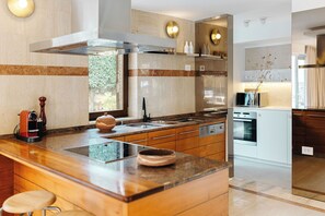 Una cocina moderna con una isla central, electrodomésticos de acero inoxidable y vistas al exterior.