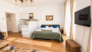 Ein Schlafzimmer mit einem Bett, einer kleinen Küchenzeile, einem Fernseher und einer Karte an der Wand.