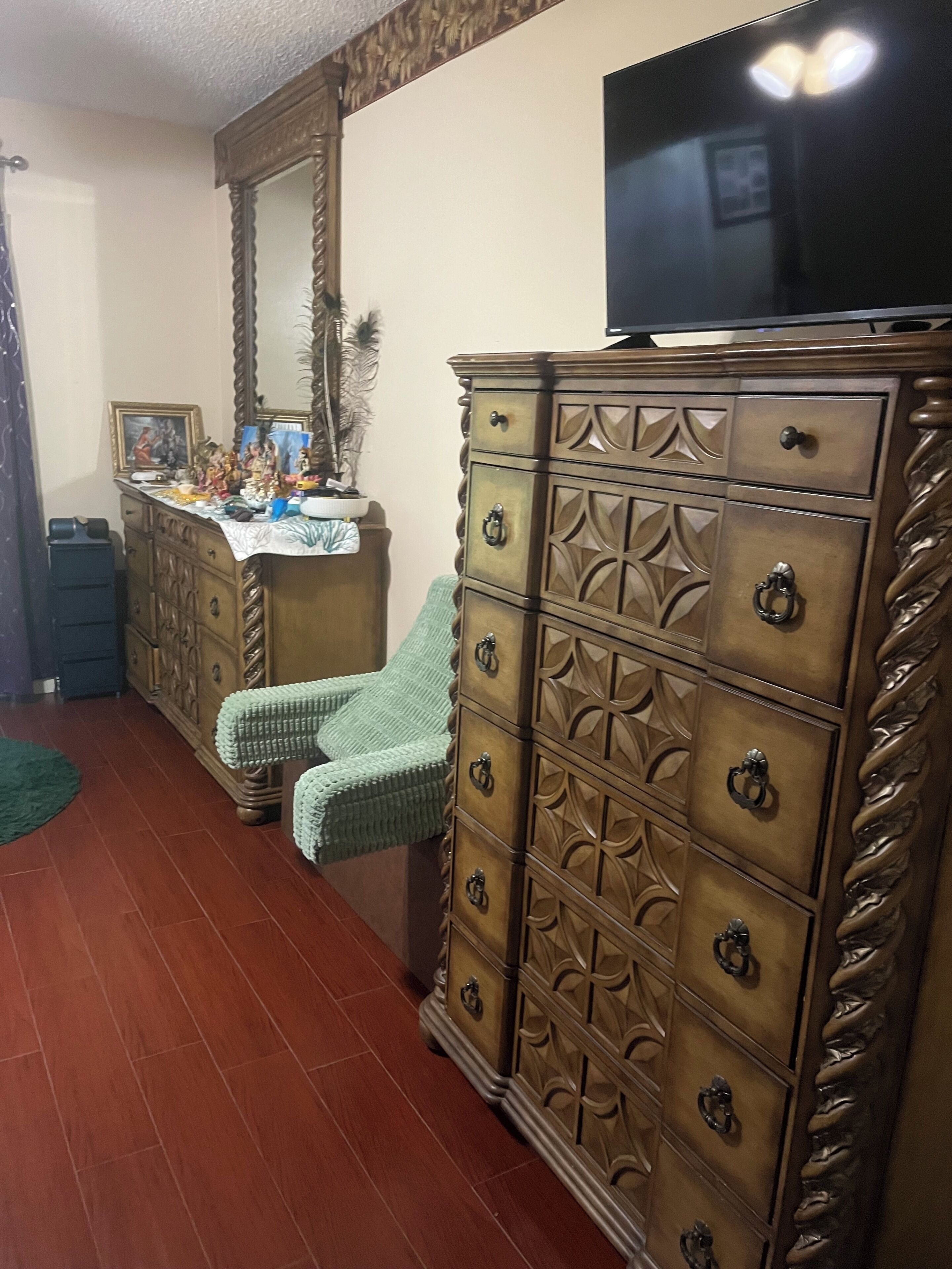 Una habitación con un aparador de madera, un televisor encima, una silla y un espejo.