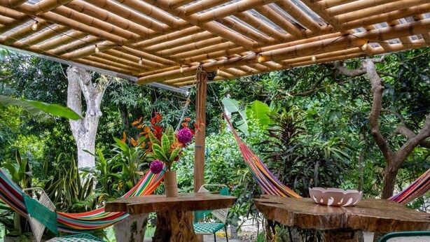 An outdoor seating area with bamboo pergola, hammocks, and chairs. - HOSTAL VILLA GUADUA TAYRONA (Santa Marta)