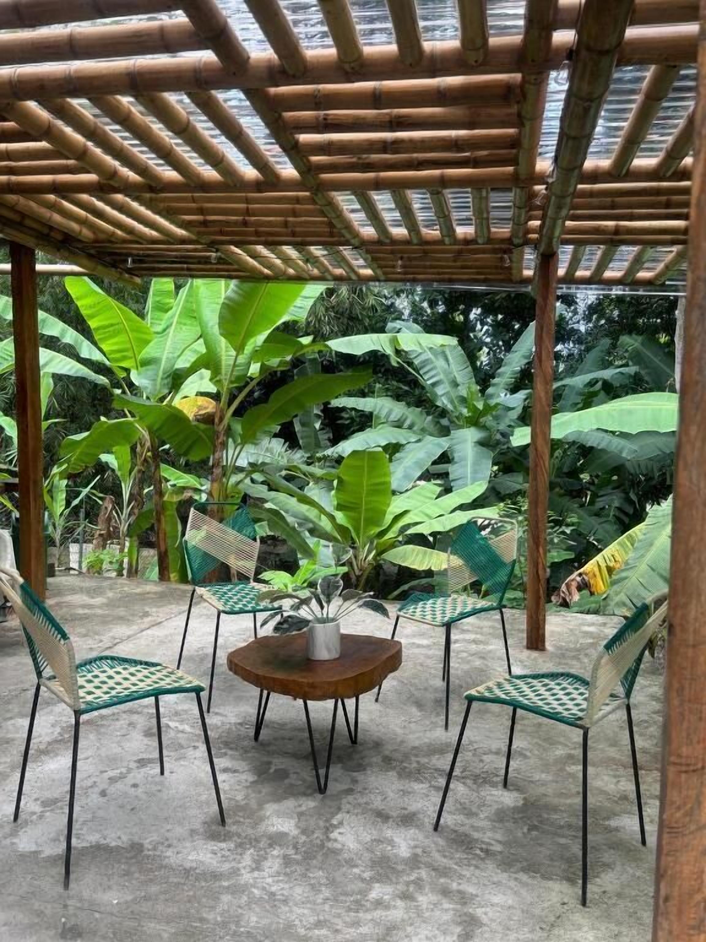 Ein Bamboopavillon mit einem runden Tisch und vier Stühlen.