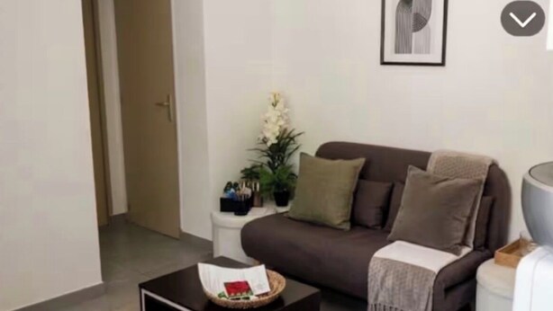 A living room with a brown sofa, a black coffee table, a white side table, and a framed picture on the wall.