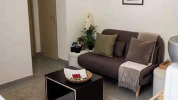 A living room with a brown sofa, a black coffee table, a white side table, and a framed picture on the wall.