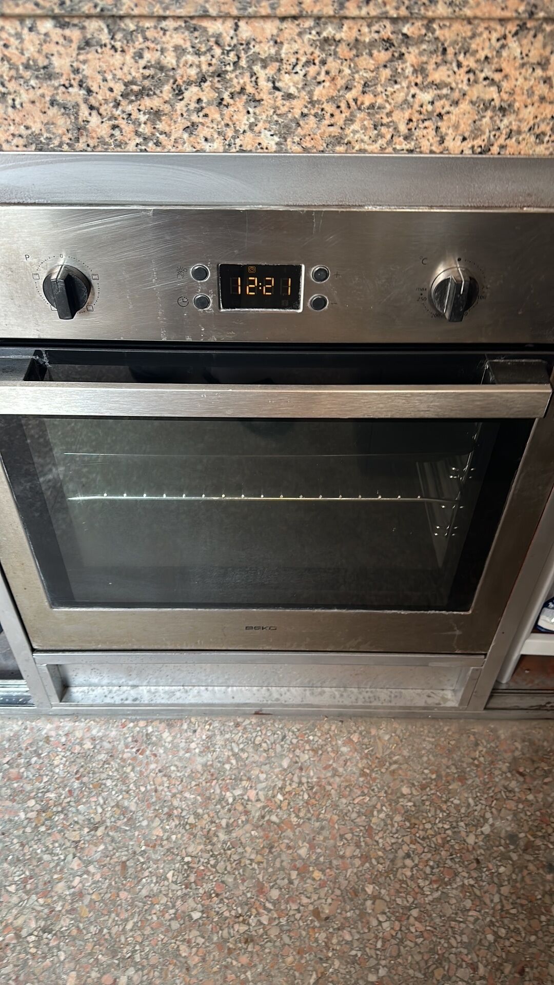 A stainless steel oven with a digital clock displaying 12:21.