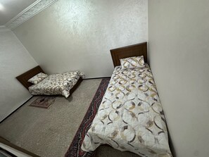 A small room with two beds, a patterned rug, and a plain wall. - Fully equipped 80 m² apartment in Agadir, located in a house with a terrace. (agadir)