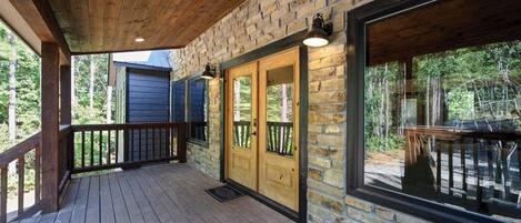 A wooden deck with stone walls and a glass door leading to an outdoor area.