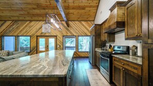 A kitchen with wooden cabinets, a marble countertop, and a large island. - Sweet Magnolia - 3BR Cozy Cabin (Broken Bow)