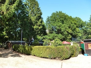 A gravel driveway leading to a building with a red roof, surrounded by dense green trees. - Waldfrieden Vacation Home in Eichenpark-Eu (Pottum)
