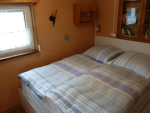Ett sovrum med en säng, ett fönster, en vägghylla och en dekoration i form av en fjäril.