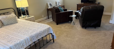 Un dormitorio con cama, mesita de noche, lámpara, cómoda, televisor y silla.
