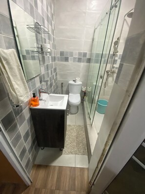 Casa de banho compacta com sanita, lavatório e chuveiro.