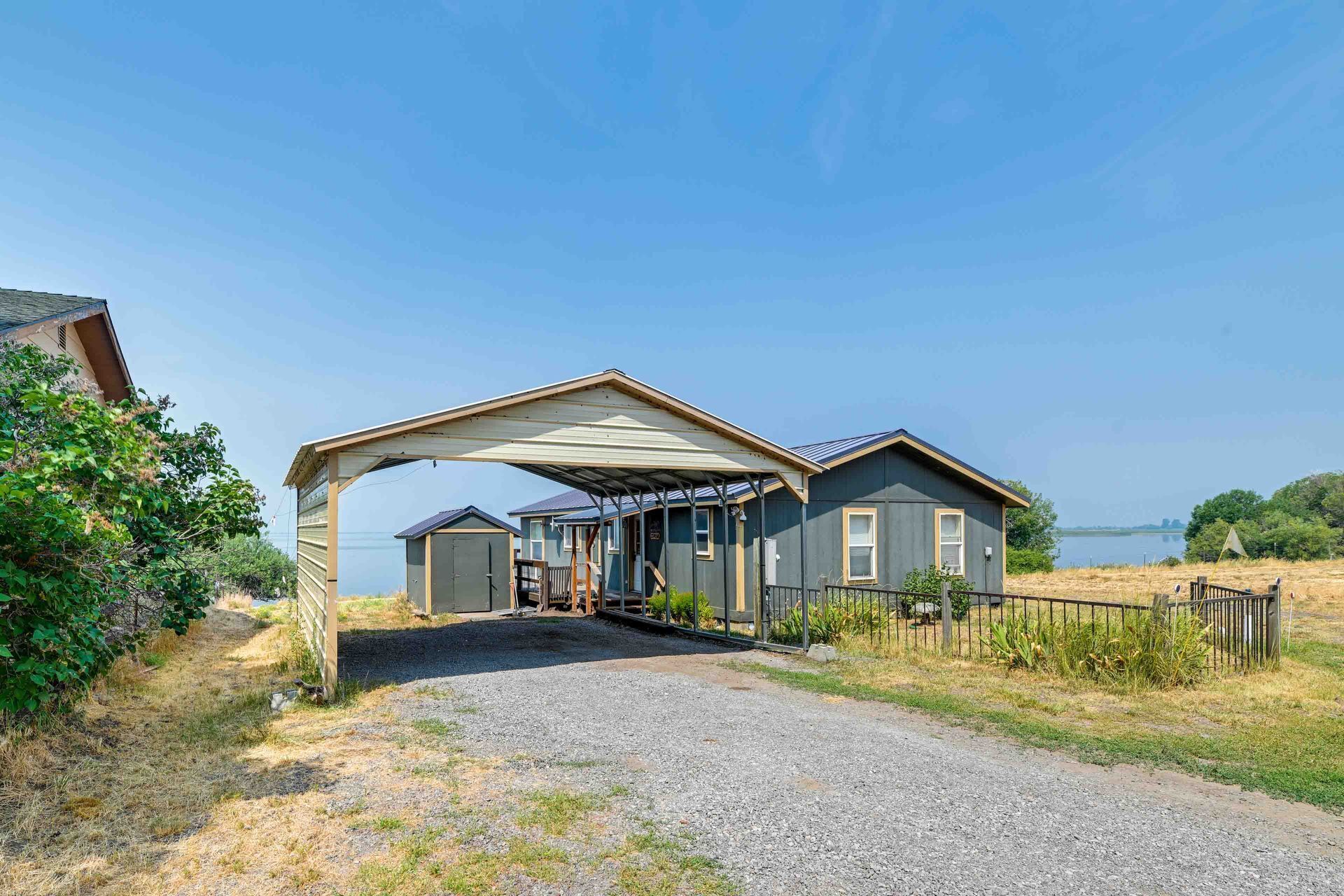 A residential property with a covered driveway, a garage, and a view of a lake.
