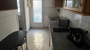 A compact kitchen with a dining area, a refrigerator, a microwave, and a toaster. - Simple, affordable studio apartment near Paris (Clichy)
