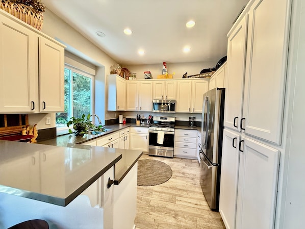 A modern kitchen with white cabinets, stainless steel appliances, and a large island.