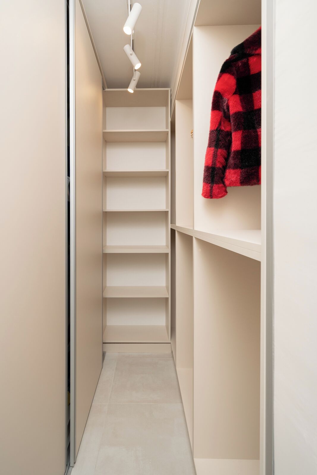 A narrow hallway with a built-in closet featuring multiple shelves and a hanging space.