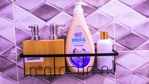 A bathroom shelf with a wooden soap dish, a pump bottle of shower gel, and a white bottle. - Luxury Kimana Stay Near Amboseli (Kimana)
