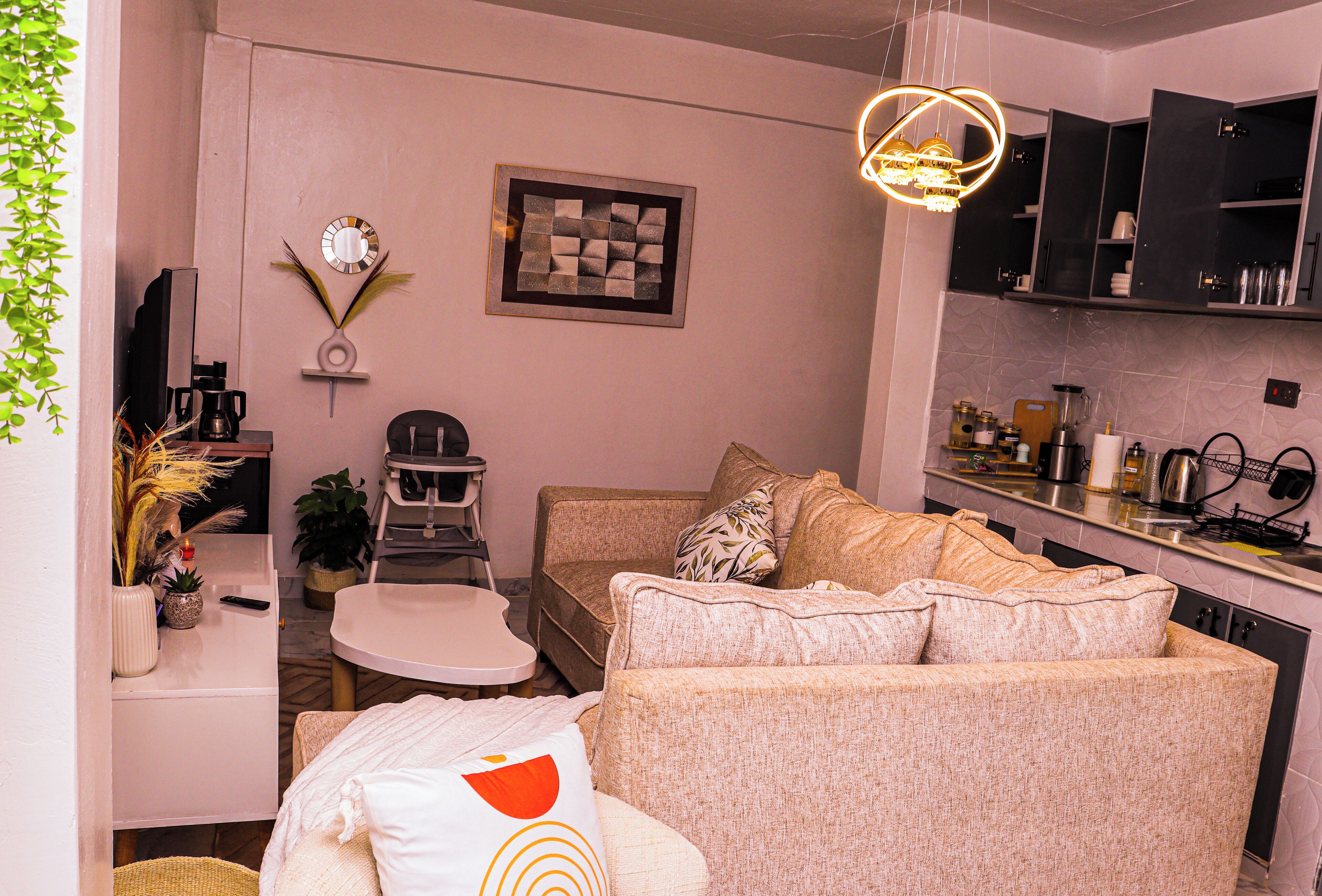 Un espacio habitable compacto con kitchenette, un conjunto de sofás, una mesa de comedor y una televisión.