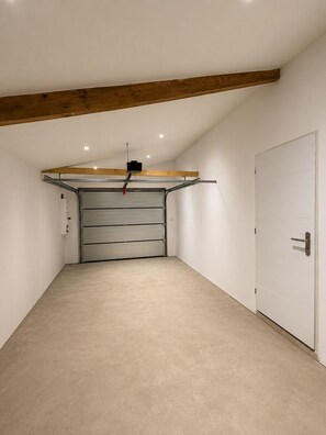 Eine Garage mit einer geschlossenen Metalldecke, einem an der Decke befestigten Projektor und einer weißen Tür rechts.