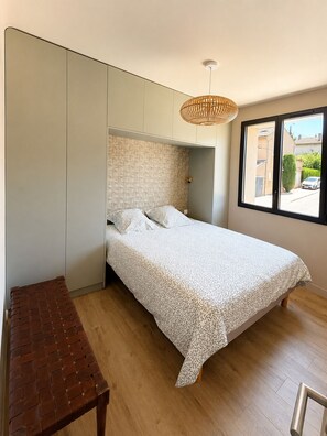 Ein Schlafzimmer mit Bett, einer Bank, einem Kleiderschrank und einem Fenster mit Blick.