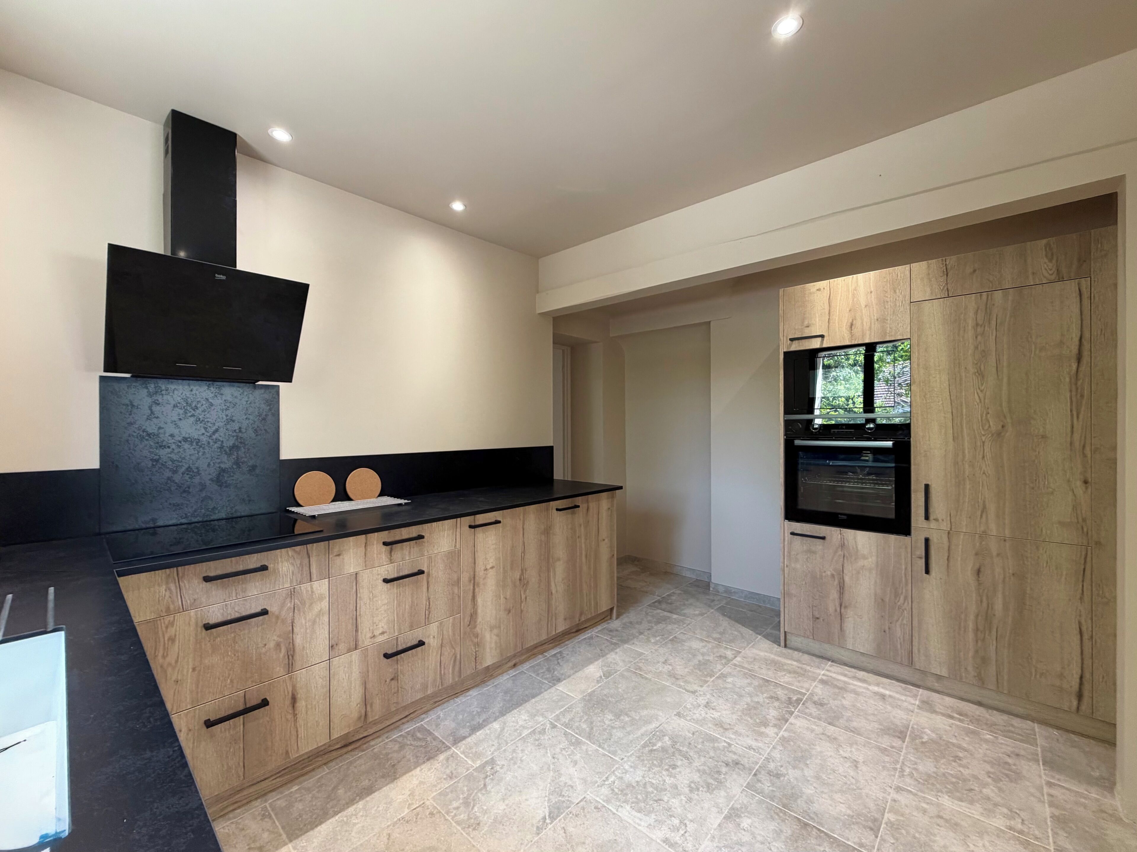 A modern kitchen with a black countertop, wooden cabinets, and a built-in oven.