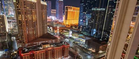 A nighttime cityscape with illuminated buildings, a prominent hotel, and a pool area.