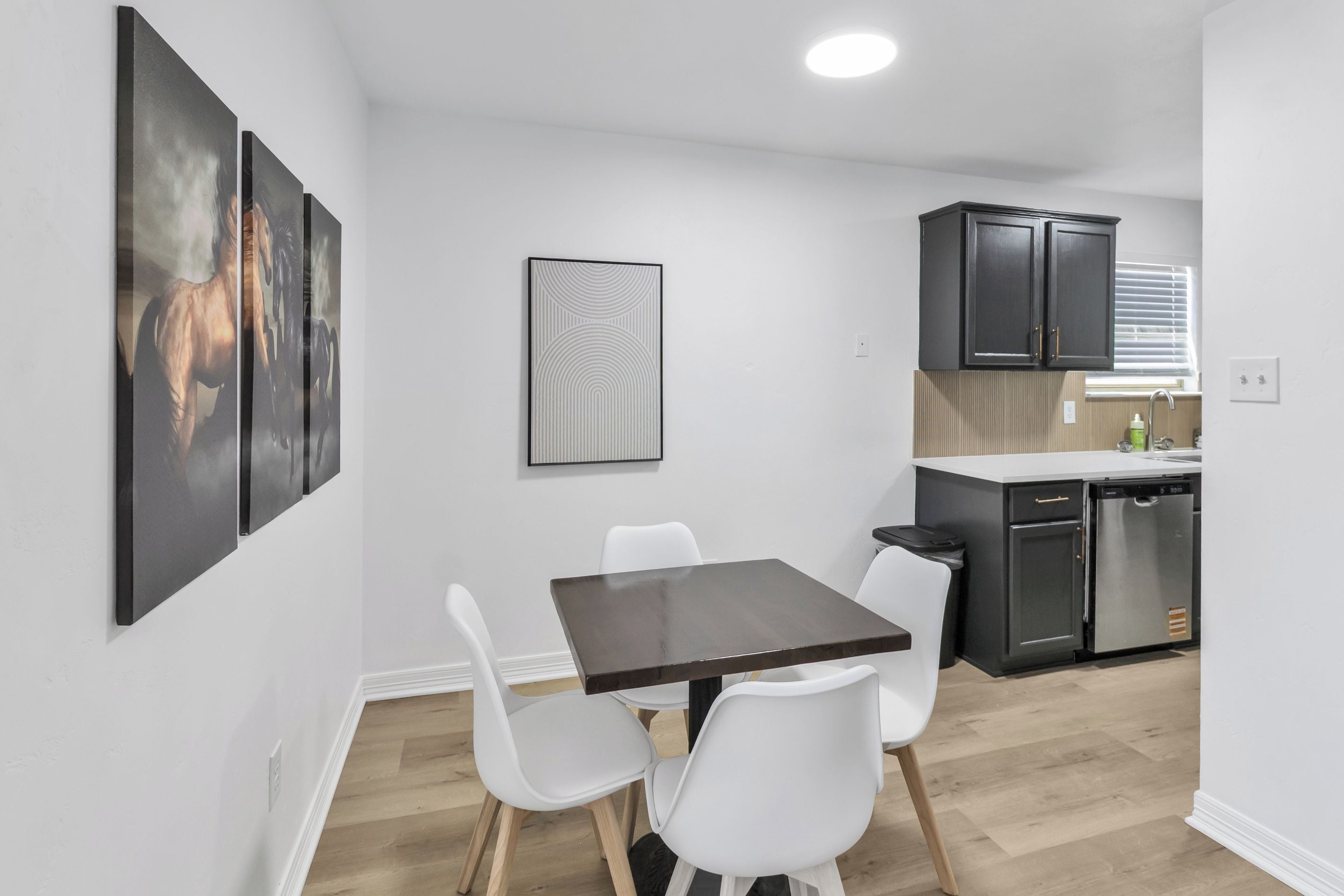 A modern kitchen with dark cabinets, a white countertop, and a dishwasher.