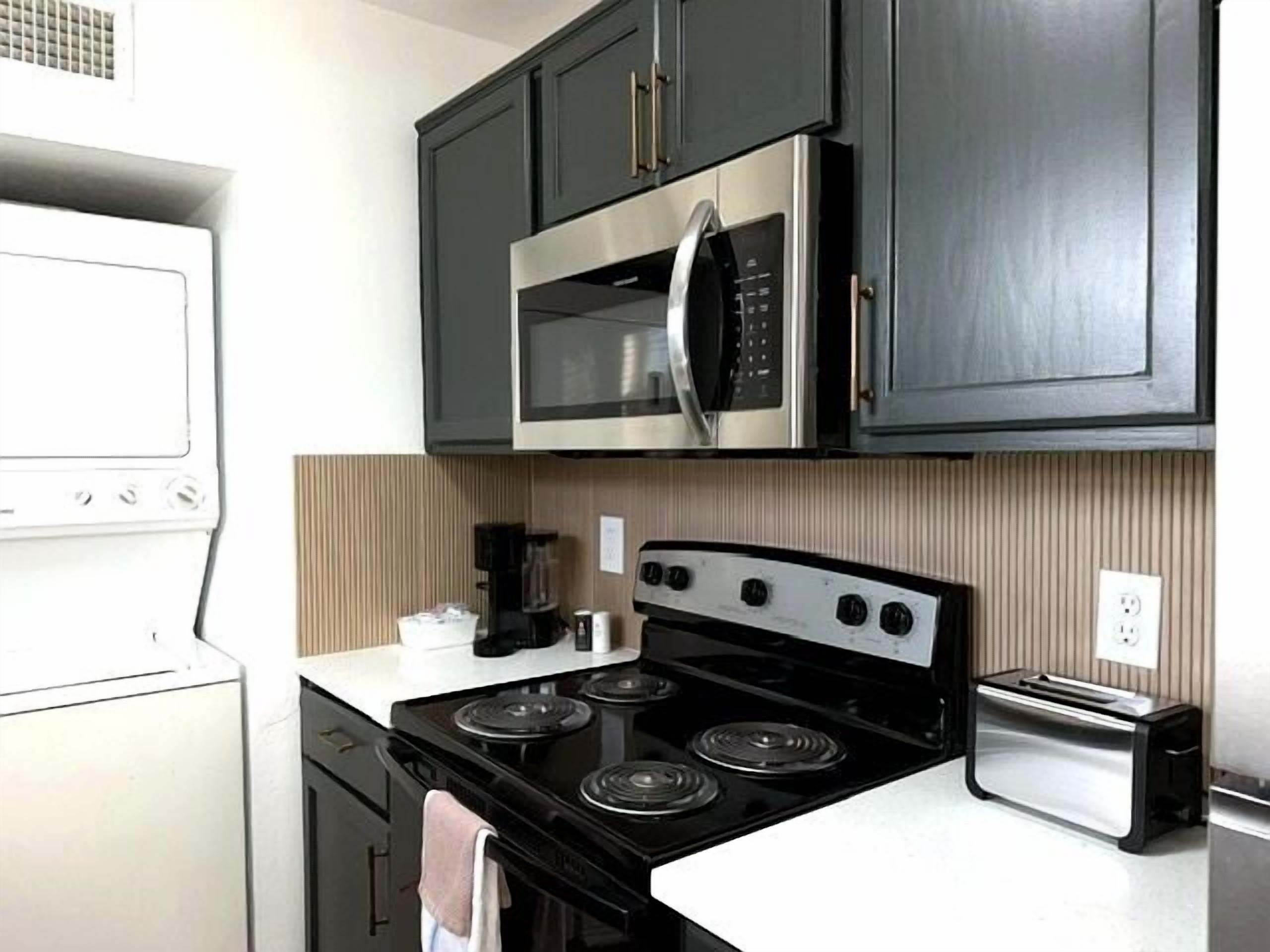 A compact kitchen with a stove, microwave, and toaster.