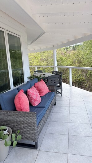 Un espace extérieur aménagé, abrité et doté d’un canapé, de chaises et d’une table.