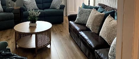 A living room with a sofa, armchair, and a round coffee table.
