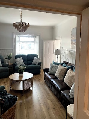 A living room with a sofa, armchair, and a round coffee table.