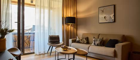 Ein modernes Wohnzimmer mit einer Couch, einem kleinen runden Tisch, einem Sessel und einer Stehlampe.